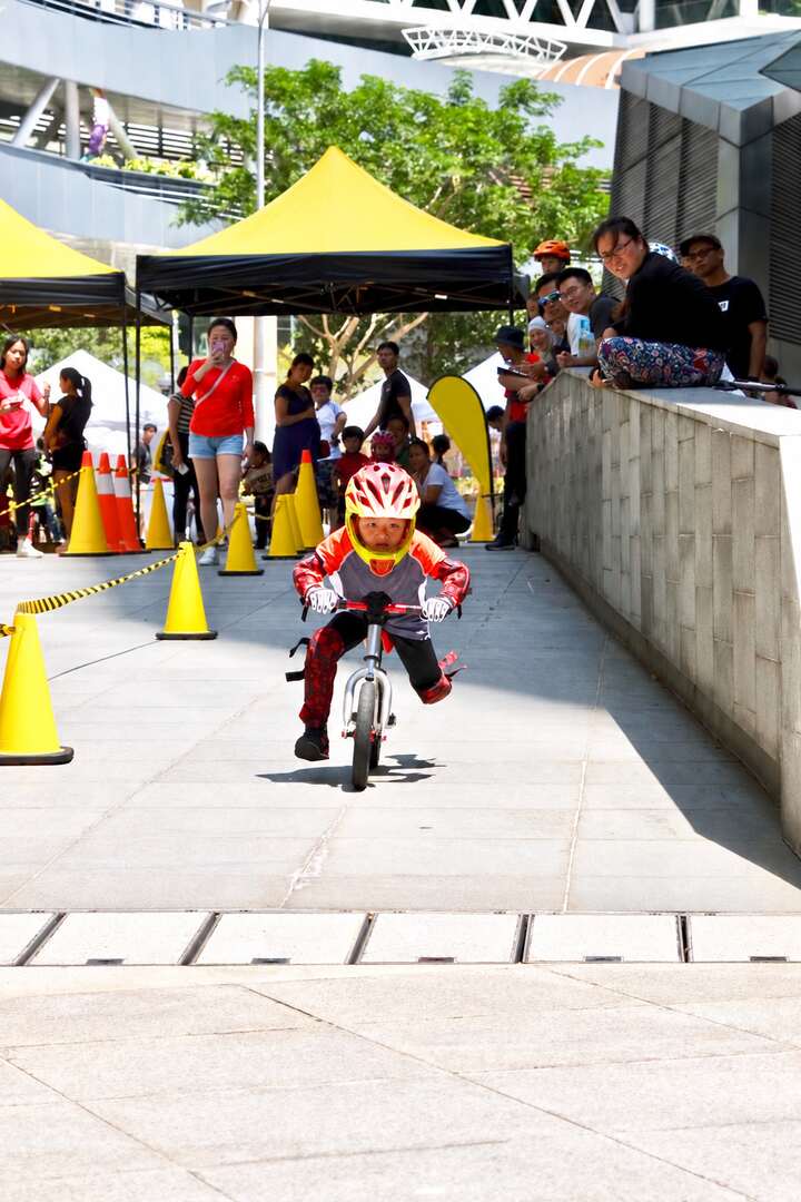 A young balance-bike rider racing towards the finish